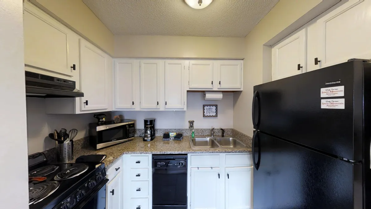 A spacious, fully equipped kitchen with a modern stove, sink, refrigerator, ample countertop space, and a coffee maker. The layout highlights the kitchen’s functionality for meal prep, cooking, and socializing, with warm lighting contributing to a homey atmosphere.