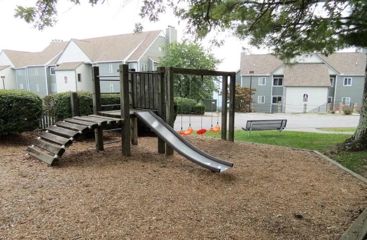 A cheerful playground with slides and swings, designed for kids to enjoy active play. The area is bathed in natural light and creates a sense of joyful community gatherings and carefree afternoons.