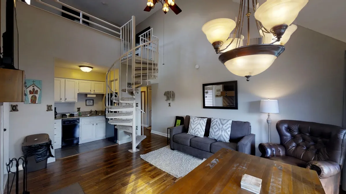 A warm, inviting living area featuring a spiral staircase, plush seating, a dining table, and a chandelier. The space radiates comfort and is perfect for cozy gatherings or relaxing after a day of adventure.